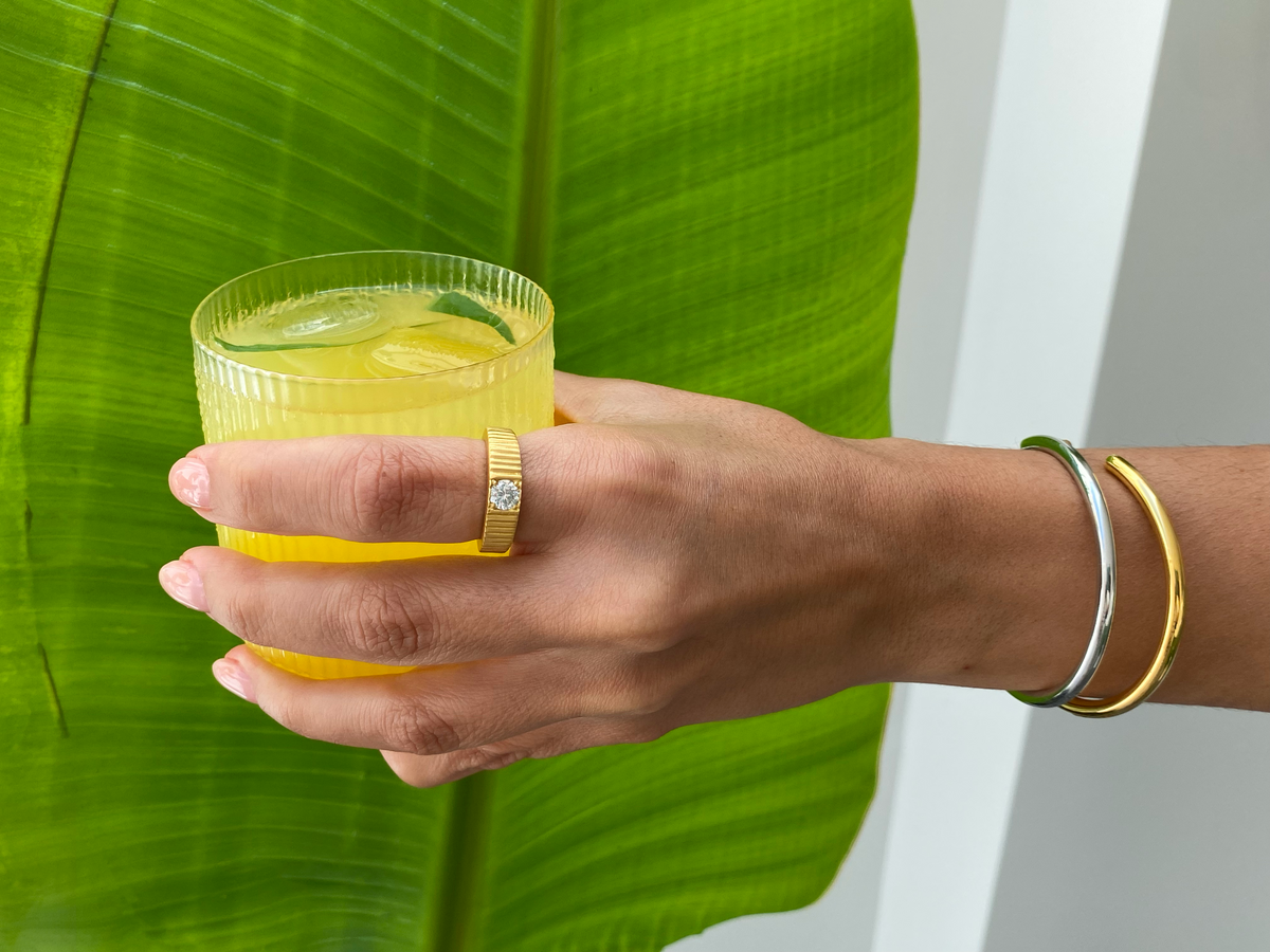 Hand holding a refreshing drink with lemon and mint, representing easy refreshing summer drinks.