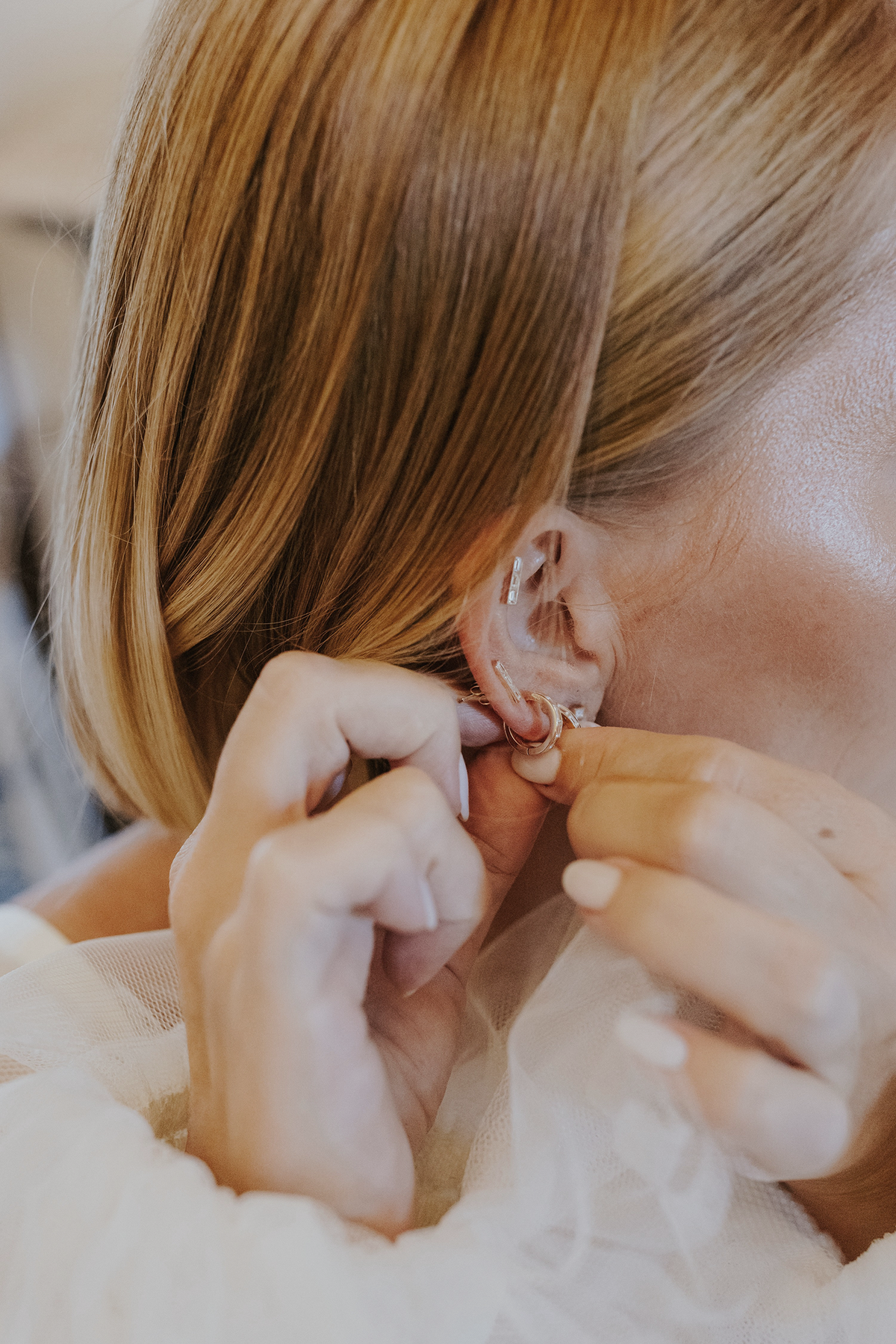Bride putting on earrings as part of her bridal jewelry guide.
