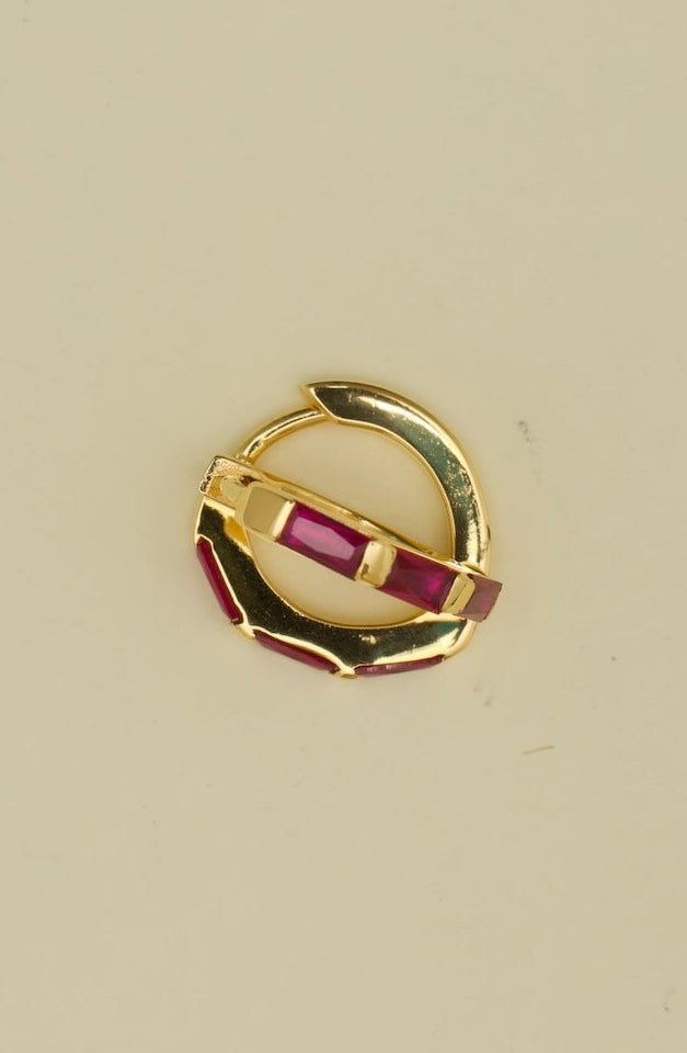 Gold ring with red gemstones on a beige background