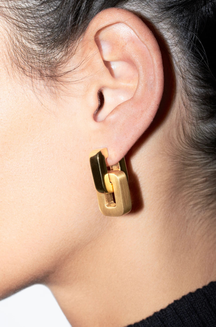 Gold hoop earring worn by a person with a neutral background