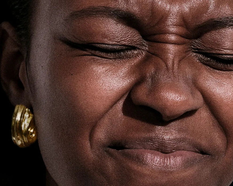Close-up of a person with a sad expression, wearing gold hoop earrings.