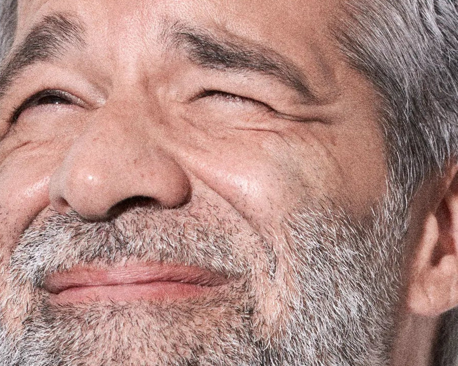 Close-up of a person with gray hair and beard, winking.