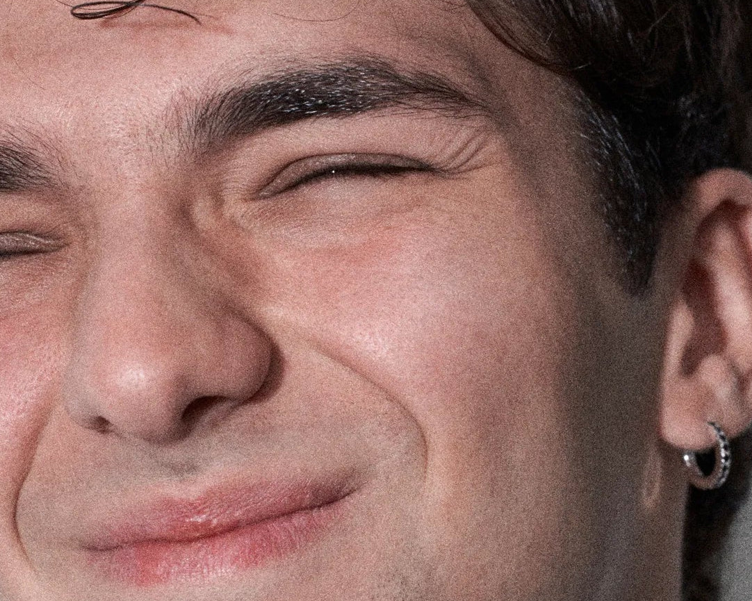 Close-up of a man's face with a slight smile, showing his ear and part of his hair.