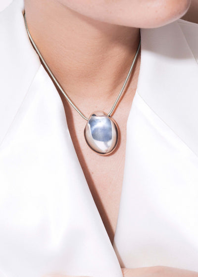 Handmade elegant Chéri necklace featuring a unique pendant worn on a model with a white blouse.