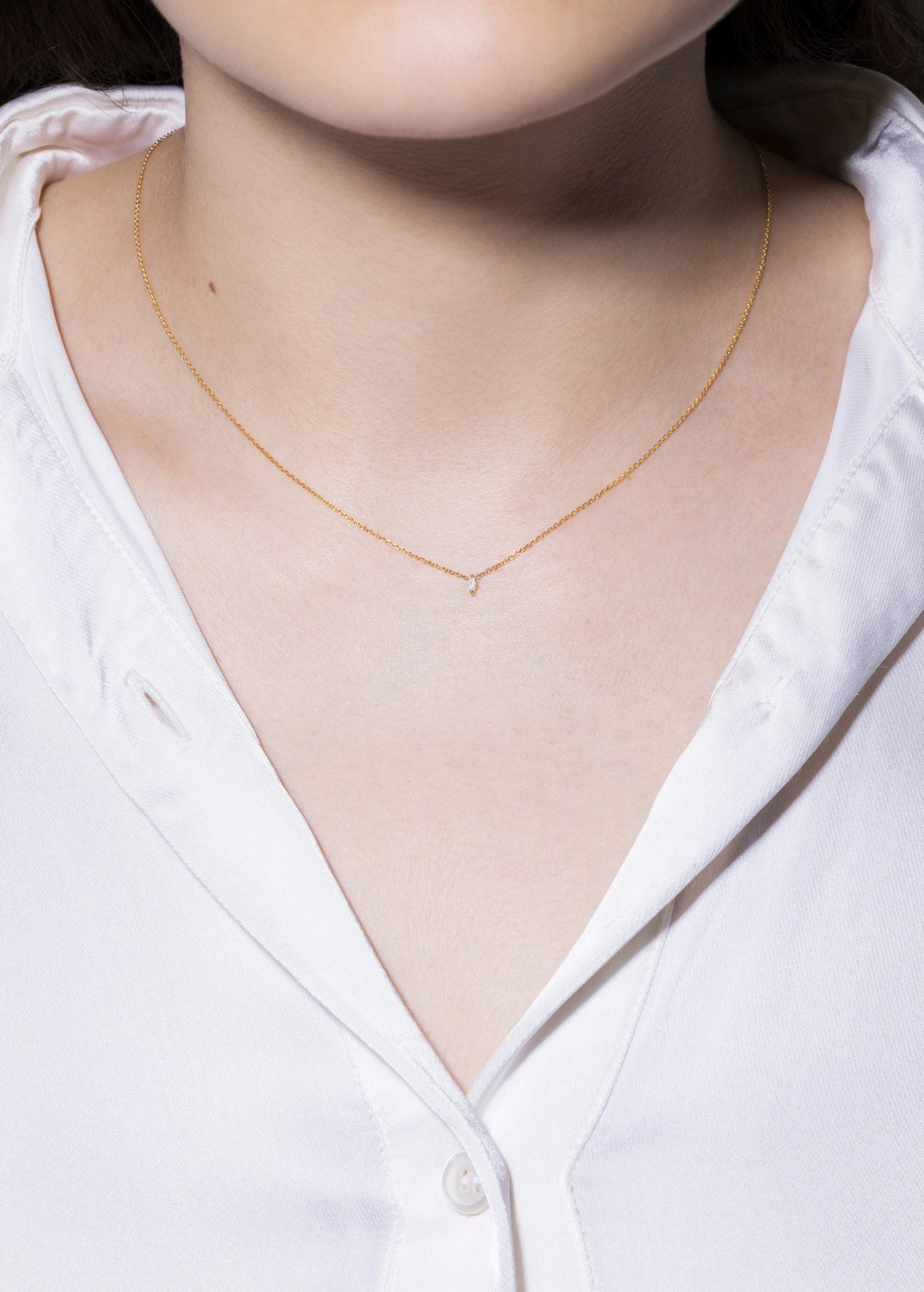 Gold necklace on a person wearing a white shirt