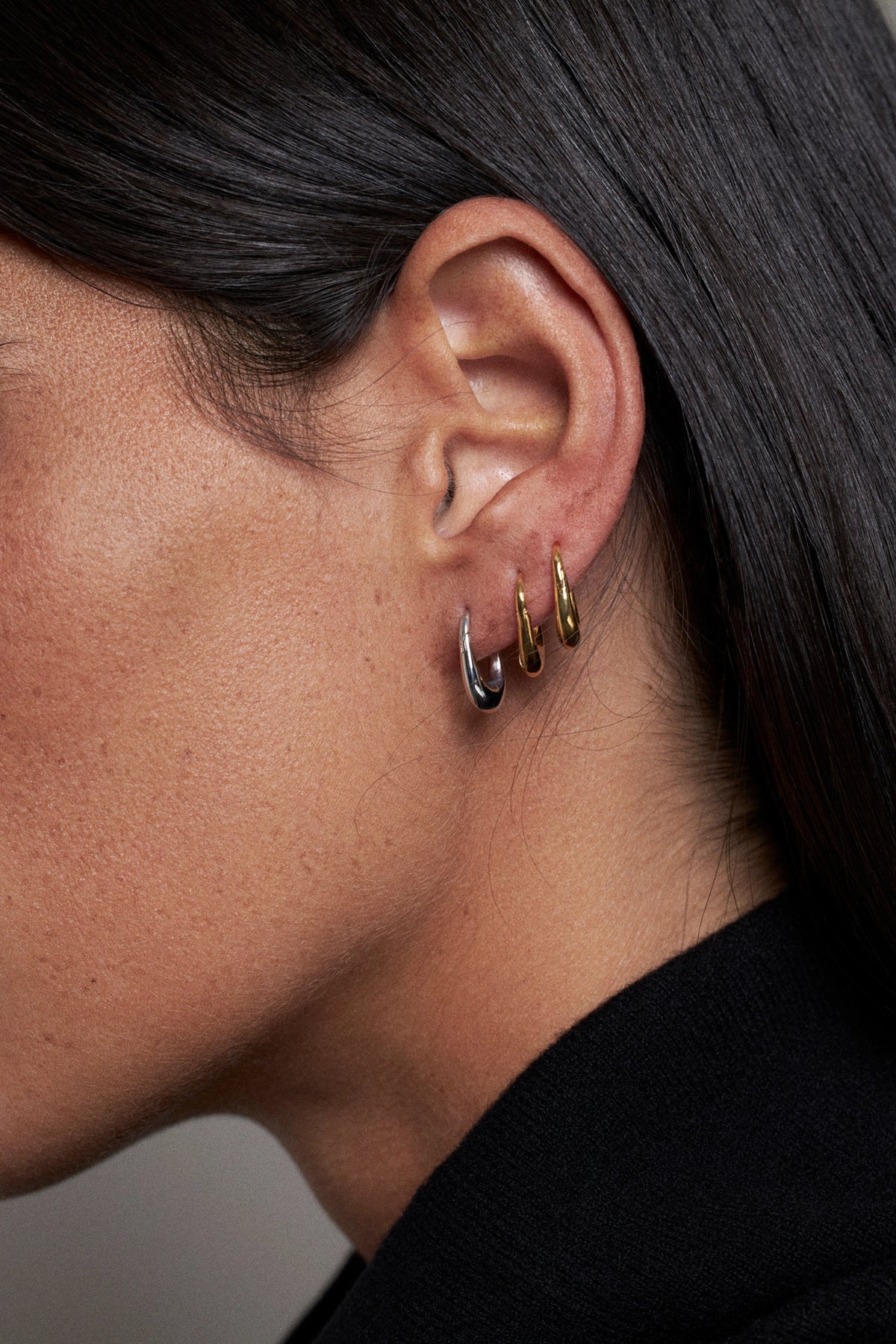CINCO elegant earrings worn on ear showcasing a mix of silver and gold tones.