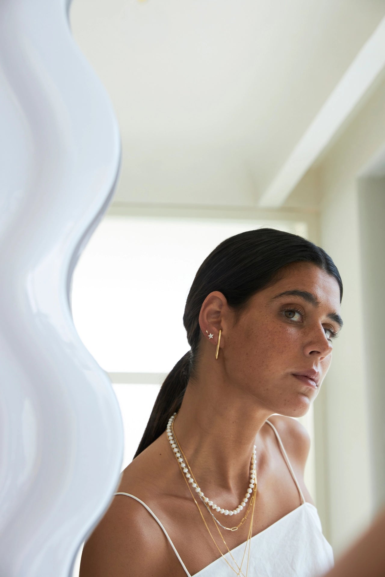 Woman wearing a pearl necklace and earrings in a neutral setting