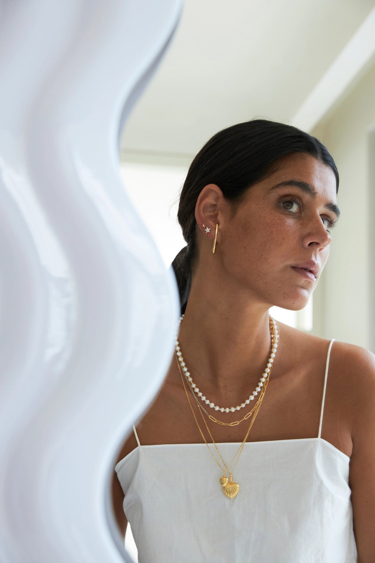 Woman wearing a pearl necklace and gold earrings with a blurred background