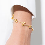 Gold bracelet on a wrist with a white background