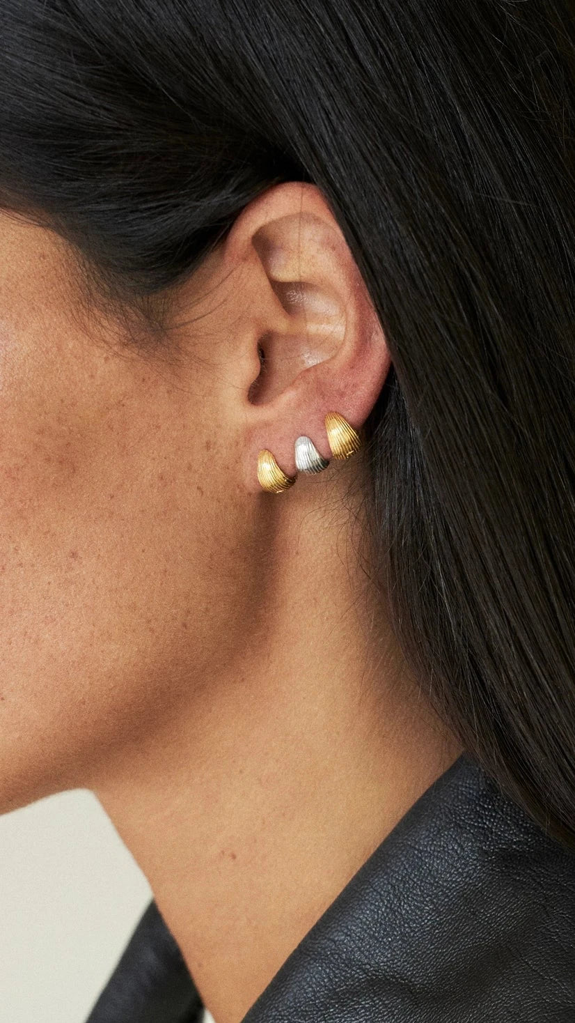 Close-up of a person wearing colorful earrings with a neutral background