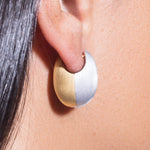 Close-up of a person wearing a two-tone gold and silver earring.