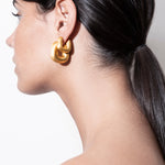 model wearing magda earrings and magda huggies in gold