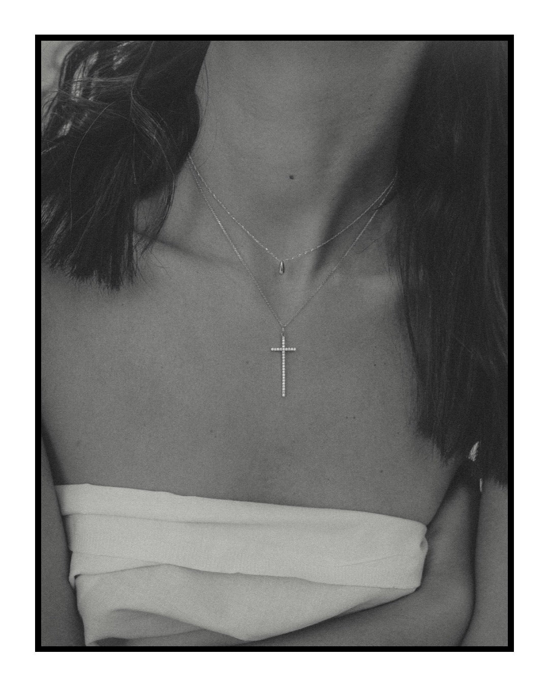 Person wearing a necklace with a cross pendant