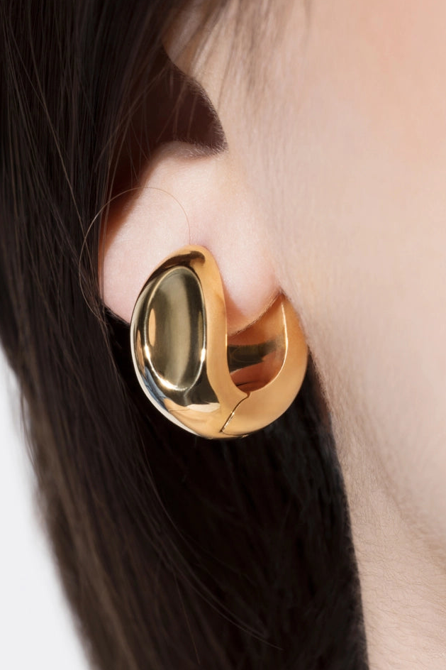Gold hoop earring worn by a person with dark hair.