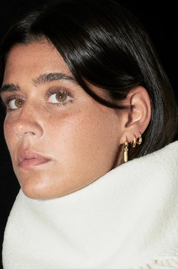 Person wearing a white turtleneck sweater with fringe details against a black background