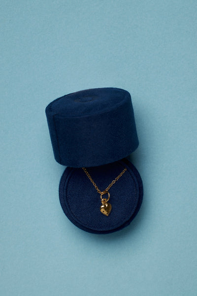 Tiny velvet jewelry box for travel showcasing a heart pendant necklace in gold.
